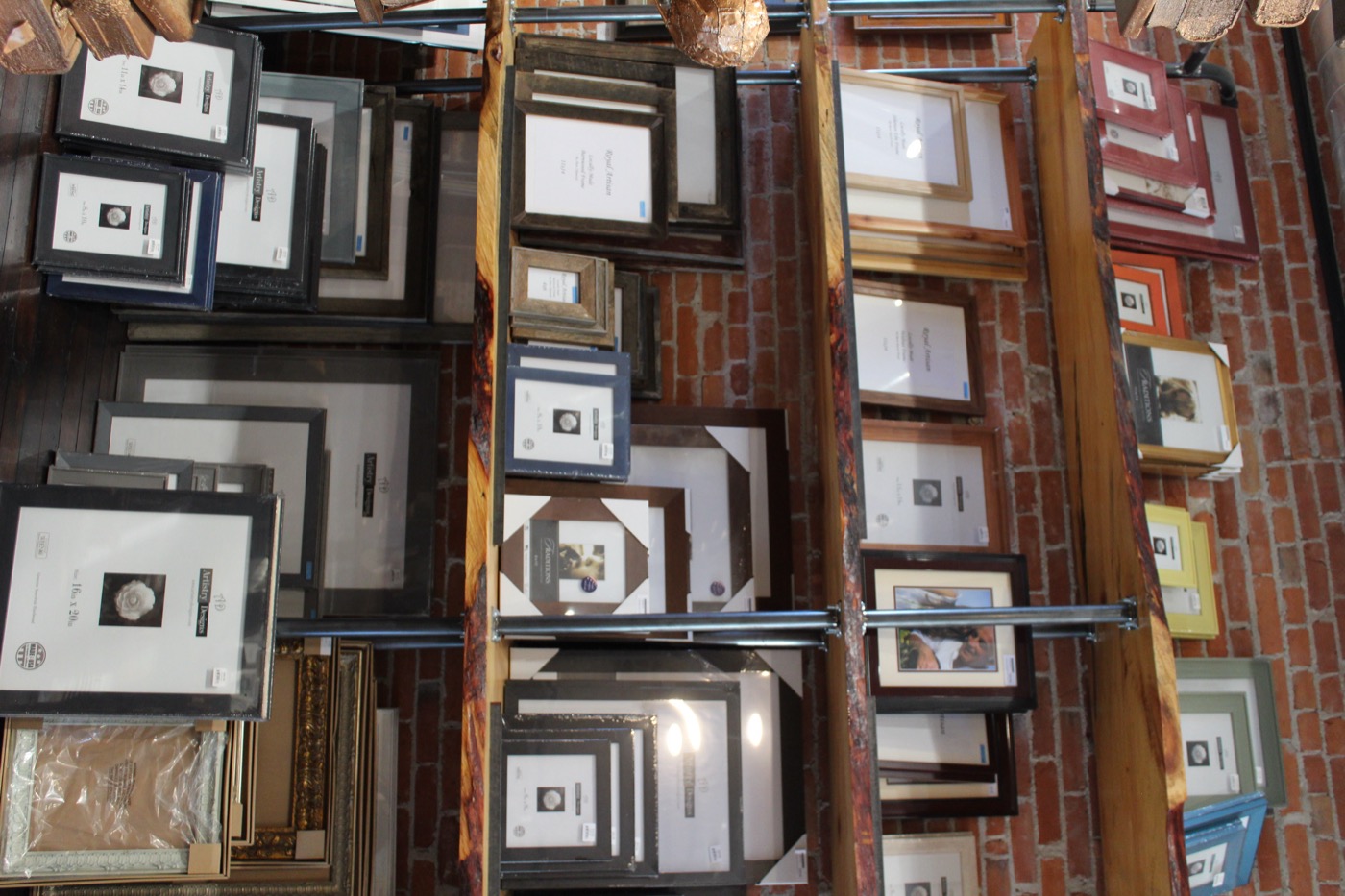 Framed pieces displayed on wood shelves against an exposed brick wall