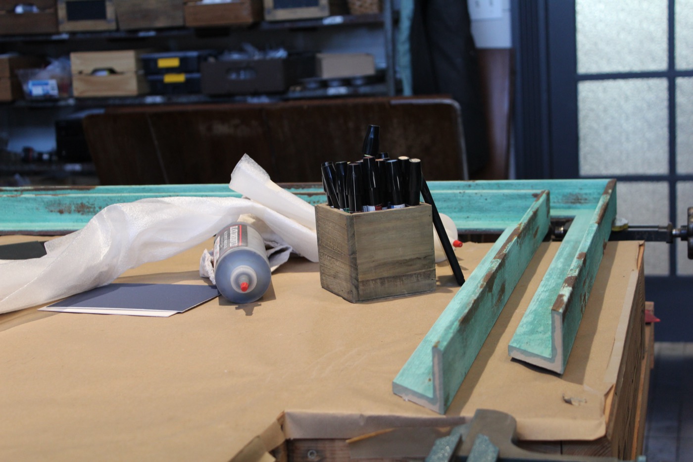 A framing workbench with tools, mat board, and turquoise frame pieces